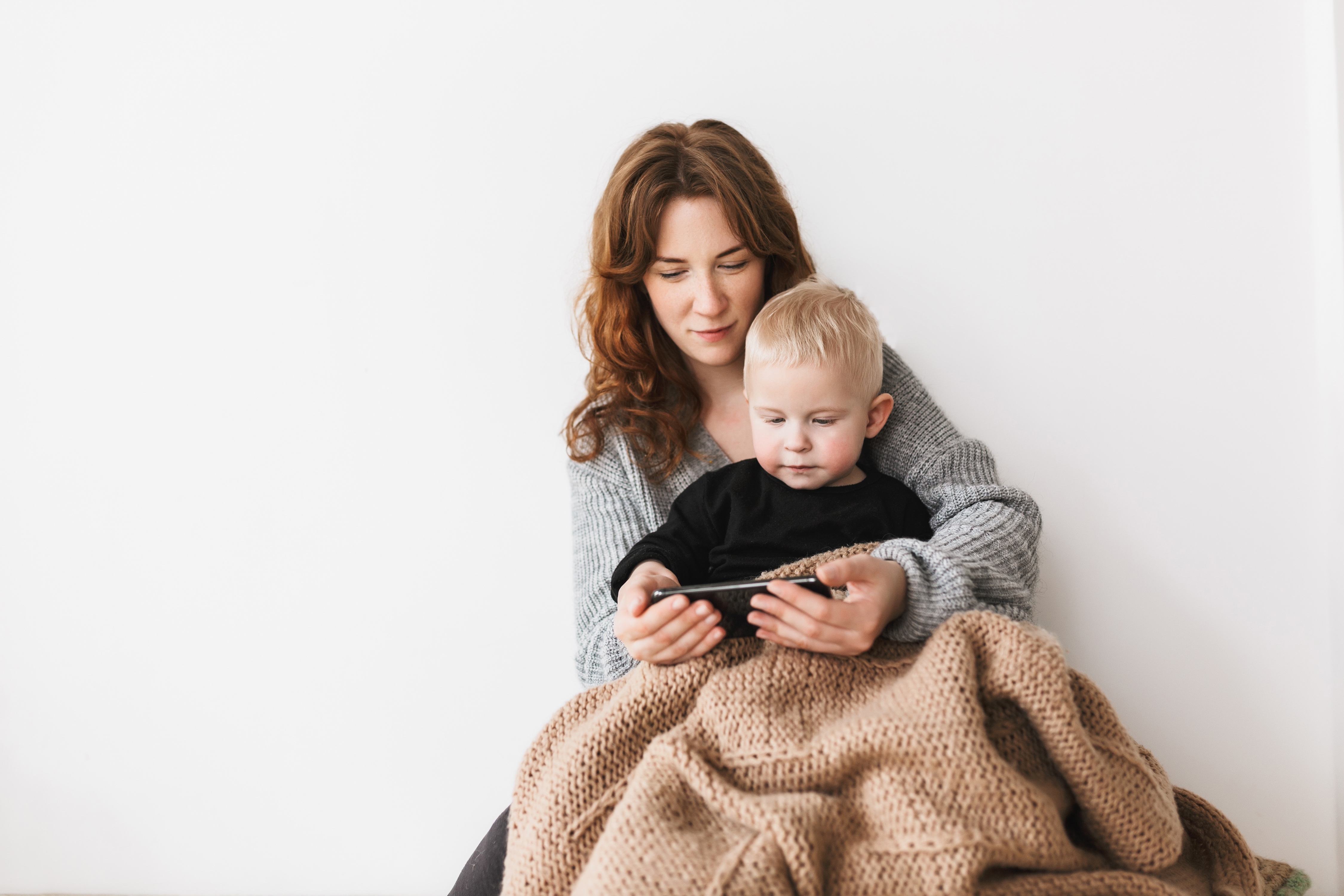 young mom in cozy sweater sitting on floor with he